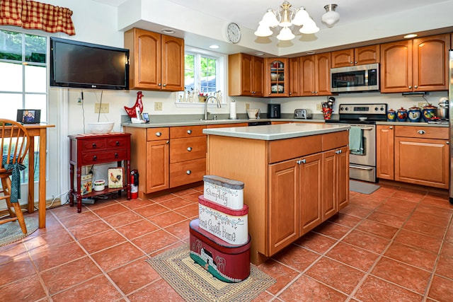 kitchen featuring sink, a chandelier, a kitchen island, dark tile patterned flooring, and appliances with stainless steel finishes