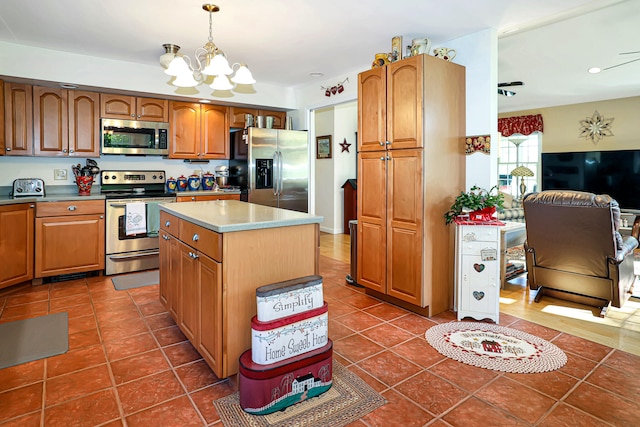 kitchen with a center island, dark tile patterned flooring, appliances with stainless steel finishes, decorative light fixtures, and a chandelier