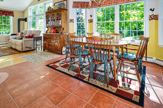 tiled dining space featuring a baseboard heating unit and lofted ceiling