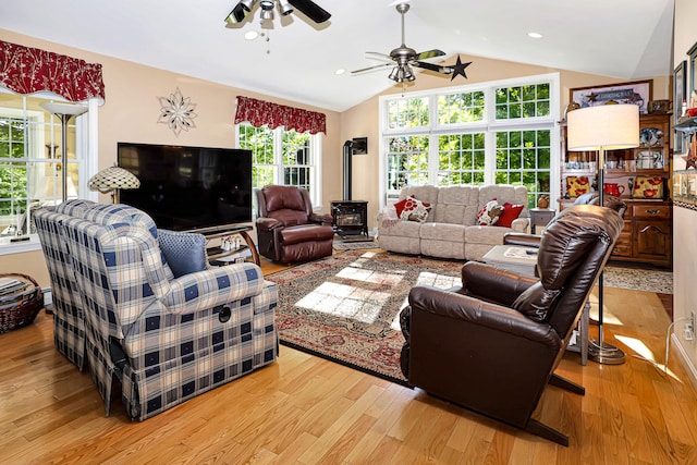 living room with a wood stove, light hardwood / wood-style flooring, and a healthy amount of sunlight