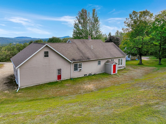 back of property featuring a lawn and a mountain view