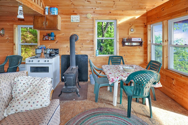 dining space featuring wood ceiling, a wood stove, and wooden walls