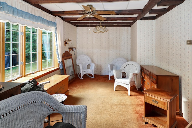 sitting room with carpet flooring, ceiling fan, and beamed ceiling