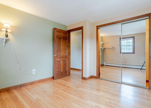 unfurnished bedroom featuring a baseboard radiator, light hardwood / wood-style floors, and a closet