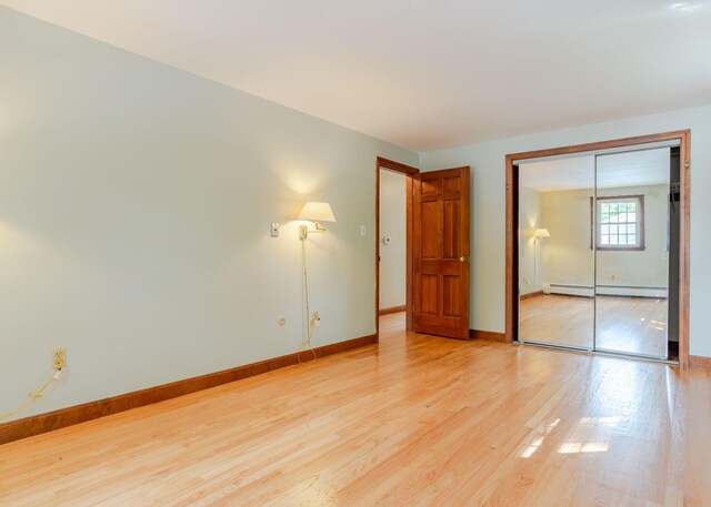 unfurnished bedroom featuring light hardwood / wood-style flooring, a closet, and a baseboard radiator