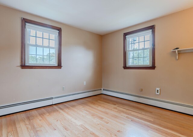 unfurnished room with baseboard heating and light hardwood / wood-style flooring