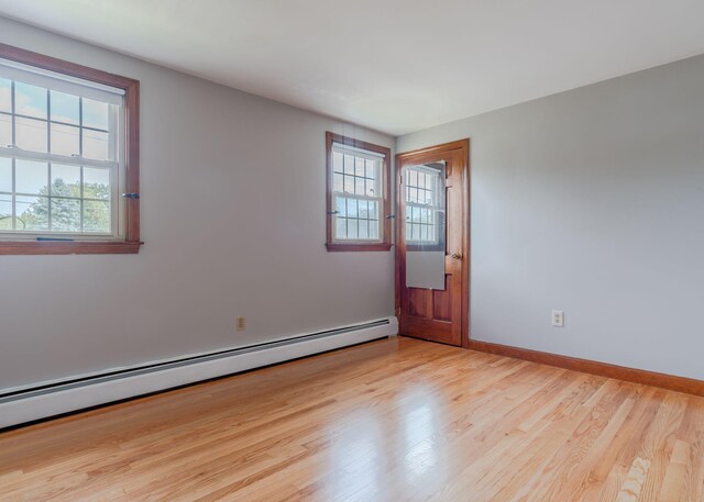 spare room featuring light hardwood / wood-style floors, a wealth of natural light, and baseboard heating