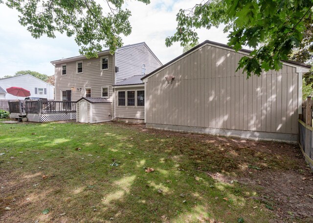 back of property featuring a deck and a lawn