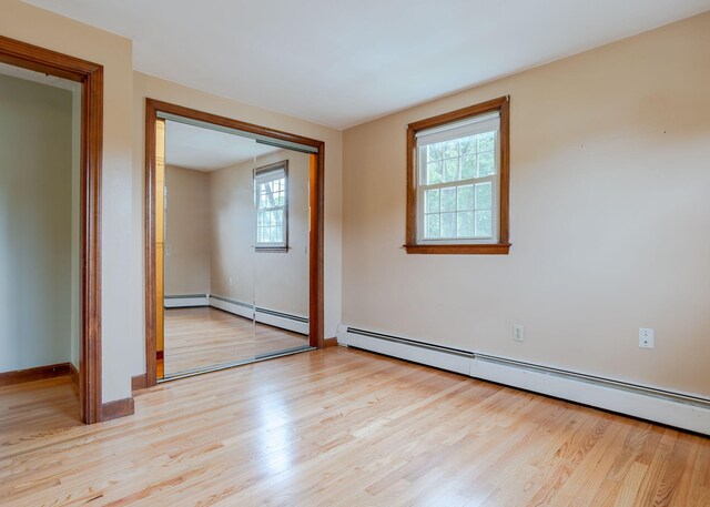 unfurnished room with light hardwood / wood-style floors, baseboard heating, and a wealth of natural light