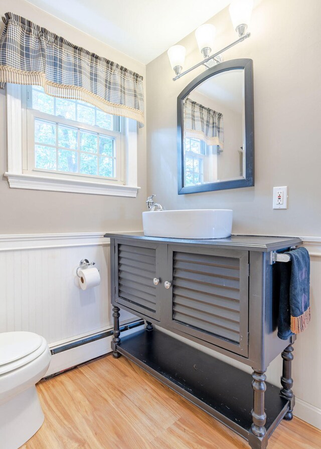 bathroom featuring vanity, toilet, hardwood / wood-style flooring, and baseboard heating