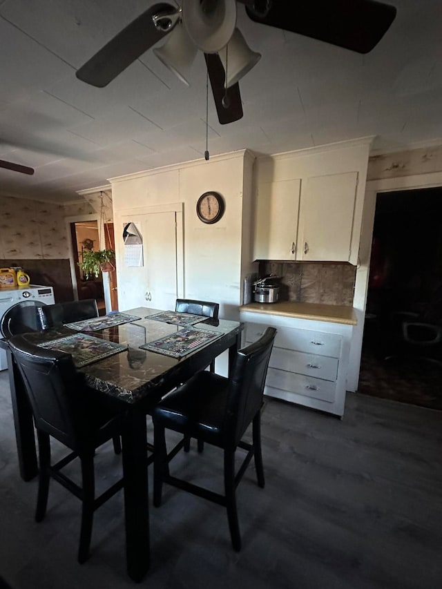 dining space with washer / dryer, wooden walls, ceiling fan, and dark hardwood / wood-style floors