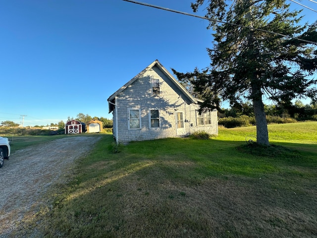 view of side of property with a storage shed and a lawn