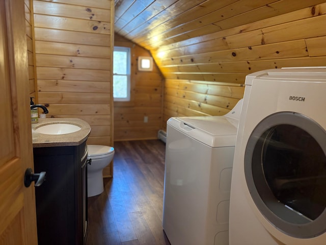 washroom with wooden walls, washer and clothes dryer, dark hardwood / wood-style floors, and sink