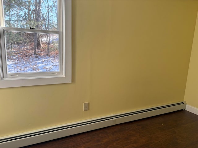 spare room featuring a healthy amount of sunlight, dark hardwood / wood-style floors, and a baseboard heating unit