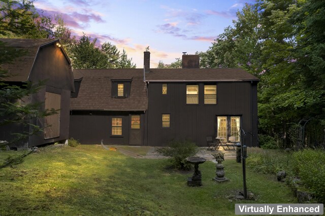 back house at dusk featuring a yard and a patio