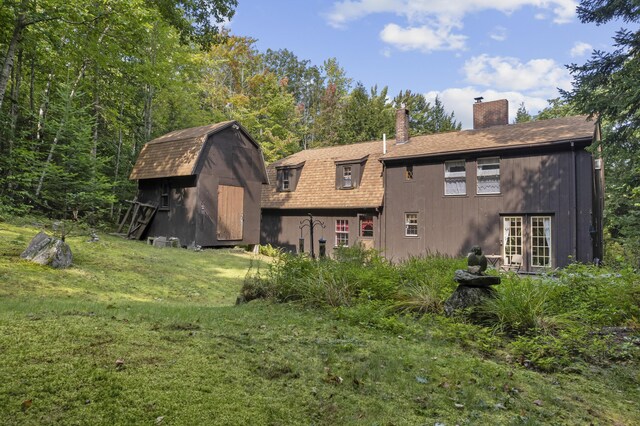 back of house featuring a lawn and a shed