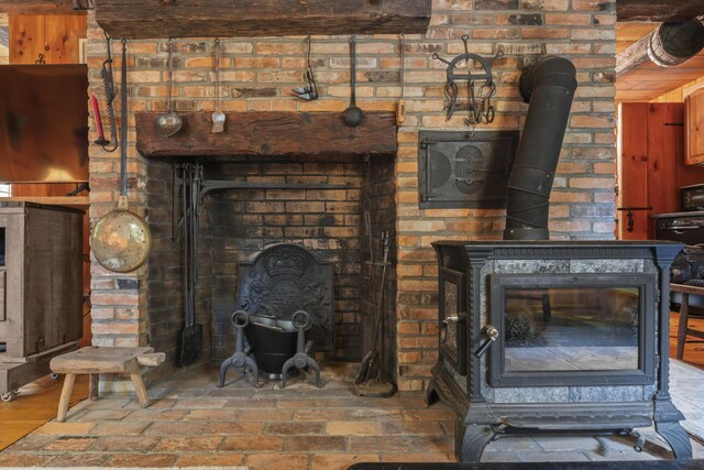 unfurnished living room with a wood stove and brick wall