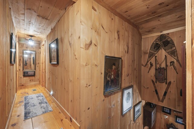 hall with lofted ceiling, hardwood / wood-style flooring, wooden walls, and wooden ceiling