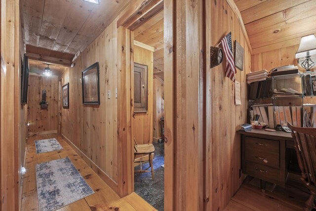 corridor featuring wooden walls, light hardwood / wood-style floors, and wooden ceiling