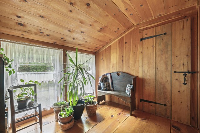 sitting room with wood ceiling, lofted ceiling, hardwood / wood-style floors, and wooden walls