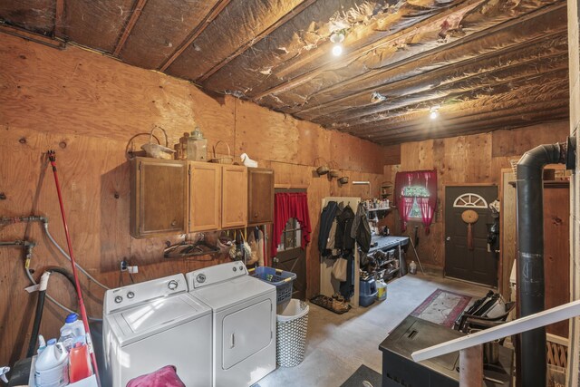 clothes washing area featuring wood walls, cabinets, and separate washer and dryer