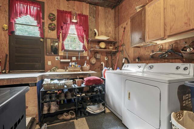 washroom with cabinets, washer and clothes dryer, and wood walls