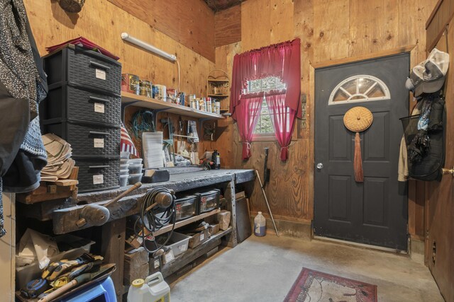 misc room featuring concrete flooring and wood walls