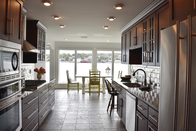 kitchen with sink, decorative backsplash, stainless steel appliances, a kitchen breakfast bar, and dark brown cabinetry