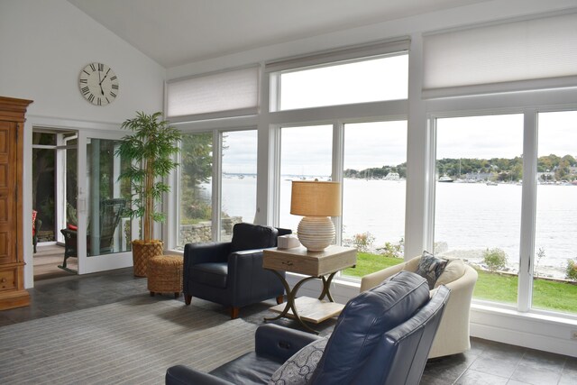 living room with dark tile patterned flooring, vaulted ceiling, and a water view