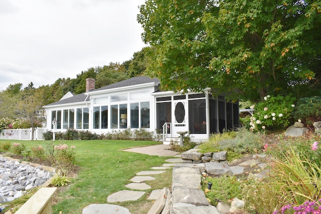 back of property with a sunroom and a yard