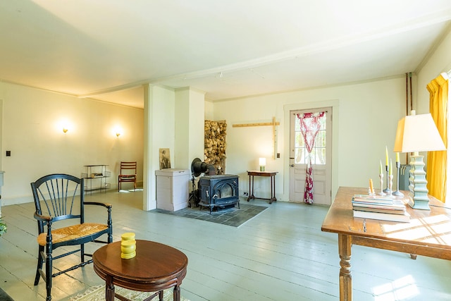 living area with a wood stove, ornamental molding, and hardwood / wood-style floors