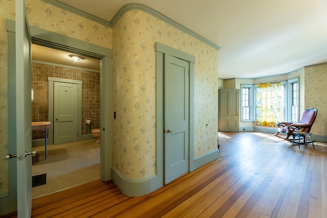 hallway featuring ornamental molding and hardwood / wood-style floors