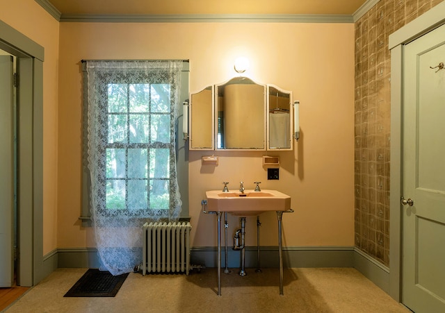 bathroom with crown molding, radiator, a healthy amount of sunlight, and brick wall