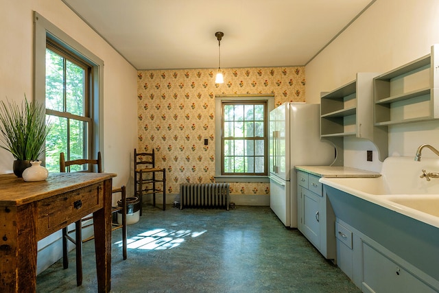 kitchen with a healthy amount of sunlight, pendant lighting, white fridge, and radiator heating unit