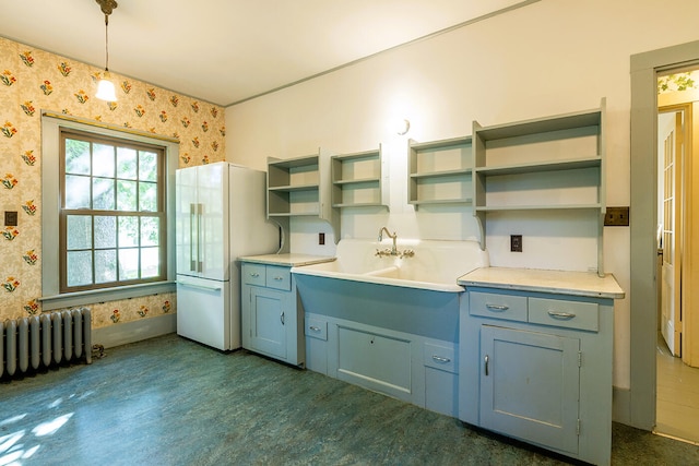 kitchen featuring radiator heating unit, white refrigerator, and decorative light fixtures