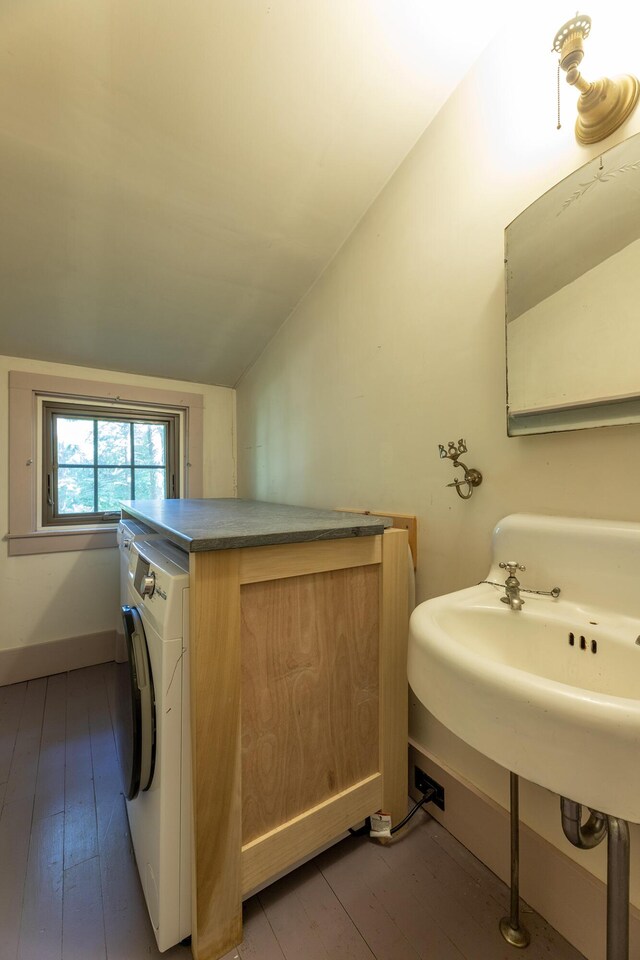 bathroom featuring washer / clothes dryer, hardwood / wood-style floors, and vaulted ceiling