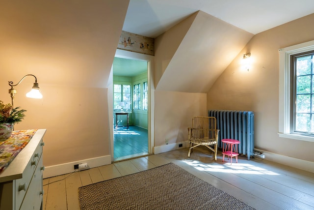 additional living space featuring radiator heating unit, vaulted ceiling, and light hardwood / wood-style floors