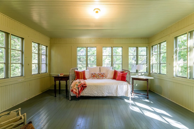 bedroom featuring hardwood / wood-style floors, wooden walls, and multiple windows