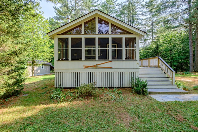 rear view of house featuring a sunroom and a lawn