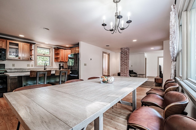 dining room with light wood-type flooring, a notable chandelier, and sink