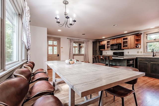 dining space with light hardwood / wood-style flooring, a chandelier, and sink