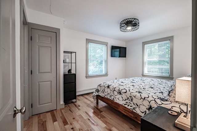 bedroom with light wood-type flooring and a baseboard radiator