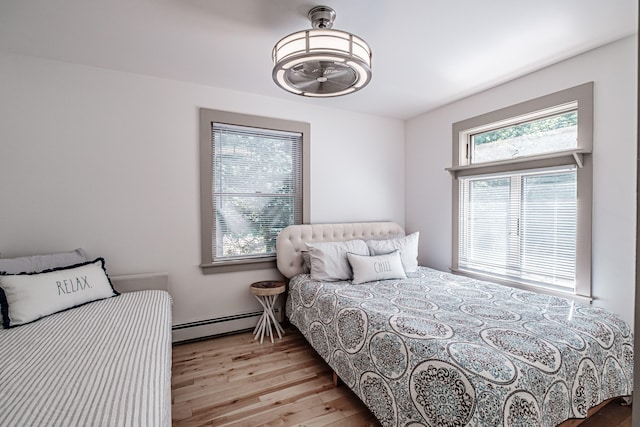 bedroom with baseboard heating and light hardwood / wood-style floors