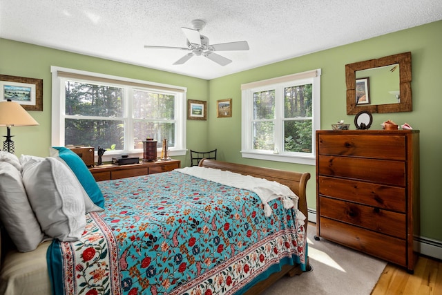 48 Camrock Dr, Rockport, ME 04856 - bedroom with multiple windows, a textured ceiling, a ceiling fan, wood finished floors, and a baseboard radiator