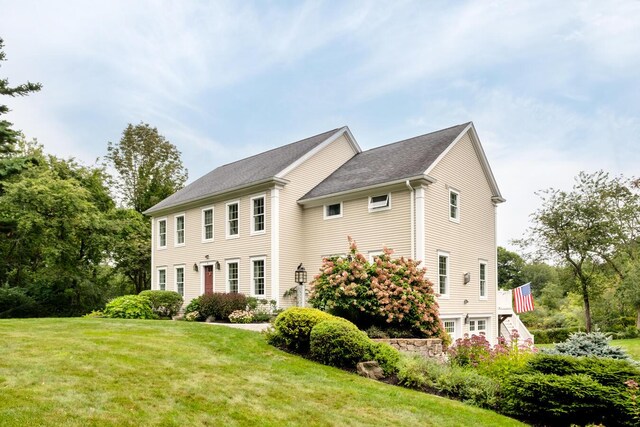 colonial inspired home with stairs and a front lawn