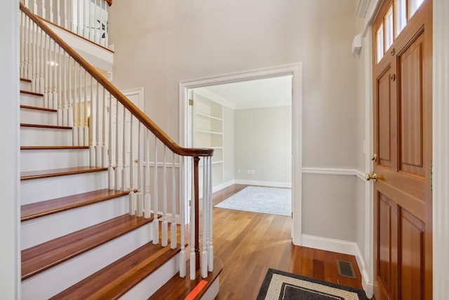 foyer featuring visible vents, stairway, wood finished floors, and baseboards