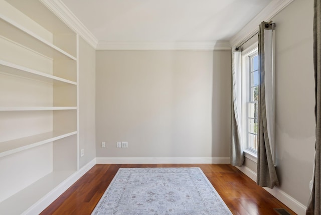 empty room featuring crown molding, dark wood-style floors, and baseboards