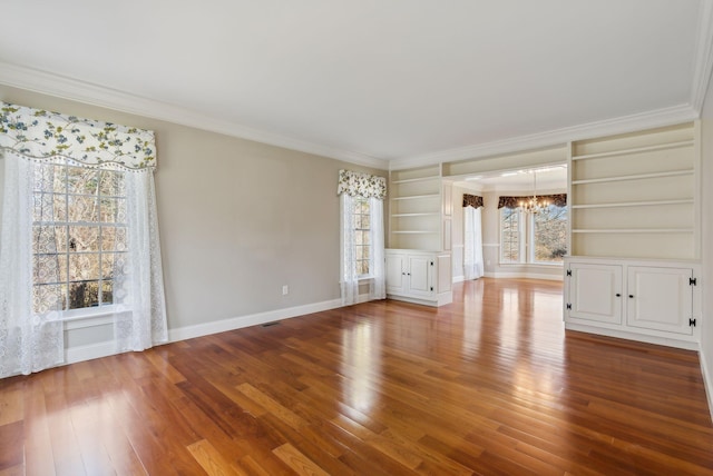 unfurnished living room featuring a healthy amount of sunlight, a chandelier, and crown molding