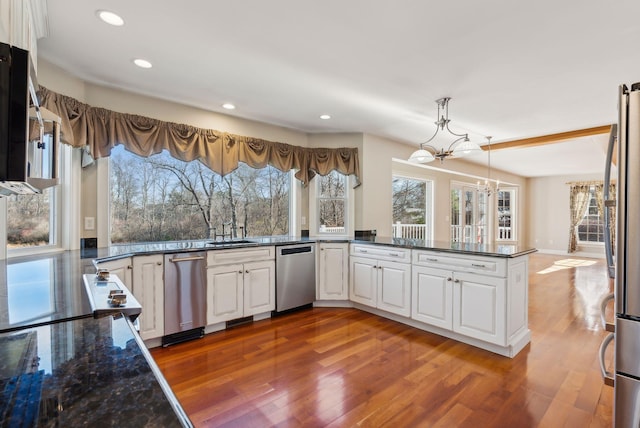 kitchen featuring decorative light fixtures, wood finished floors, a notable chandelier, white cabinets, and stainless steel appliances