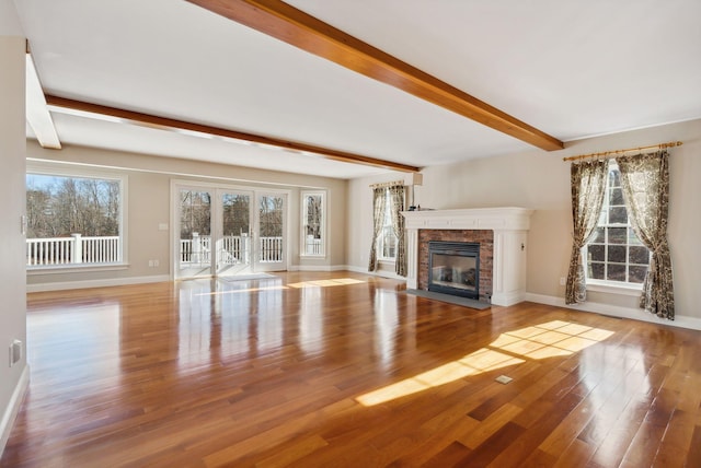 unfurnished living room featuring beamed ceiling, plenty of natural light, and wood finished floors